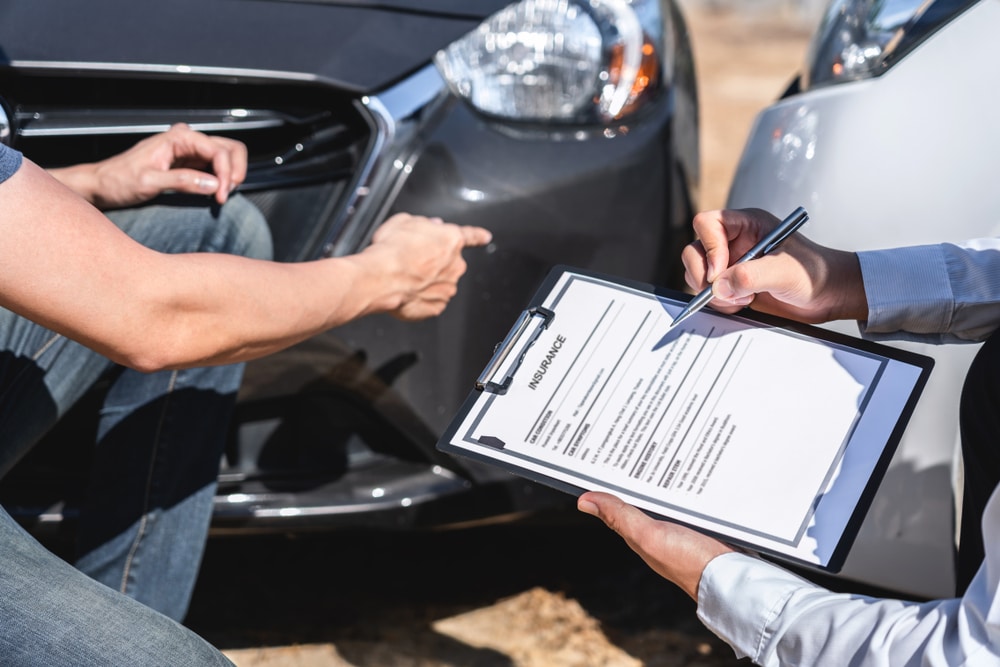 Police officer filling out car accident report after accident