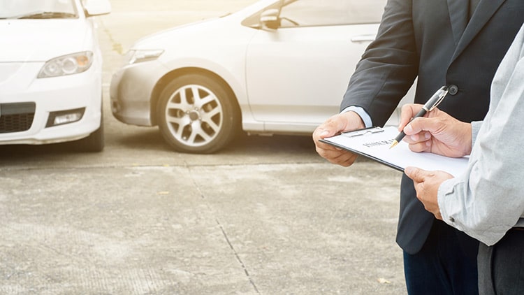 Two insurance agents discussing car accident report involving two vehicles