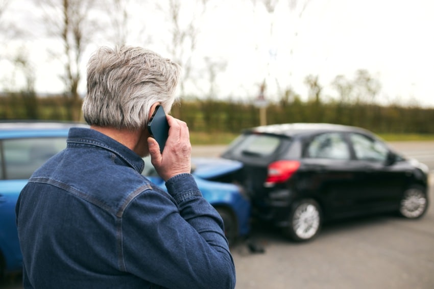 Close up of male driver calling for help after auto crash between blue and black vehicles