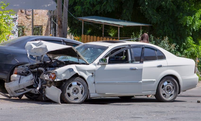 Daytime collision car accident between black car and front car with smashed front end