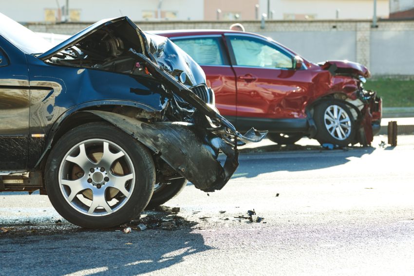 Black car red car damaged after front collision road debris during daytime