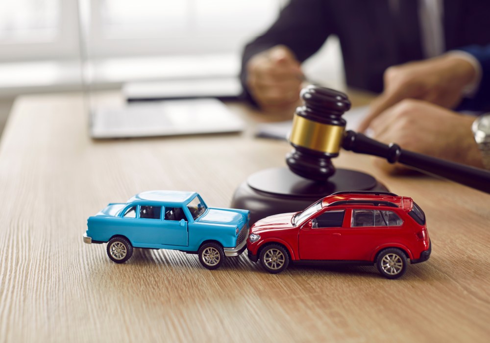 Blue red toy cars crashing on table with gavel lawyer and client in background