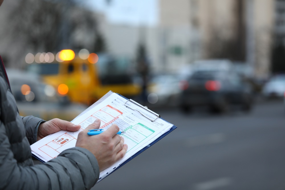 Closeup of an insurance agent completing a crash report to value losses after accident