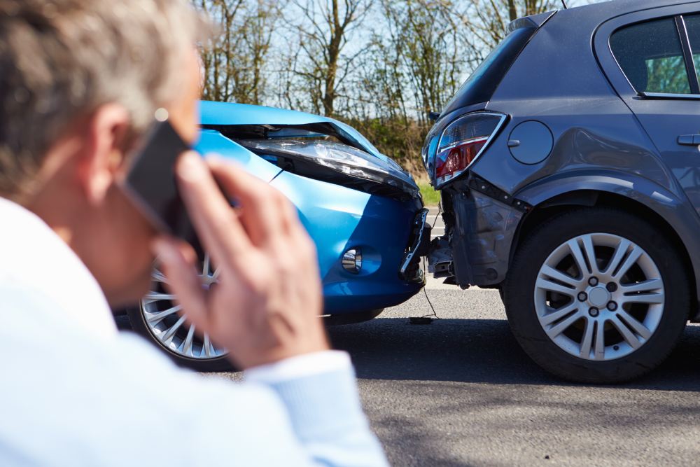 Male driver on the phone after rear collision between two vehicles on a sunny day