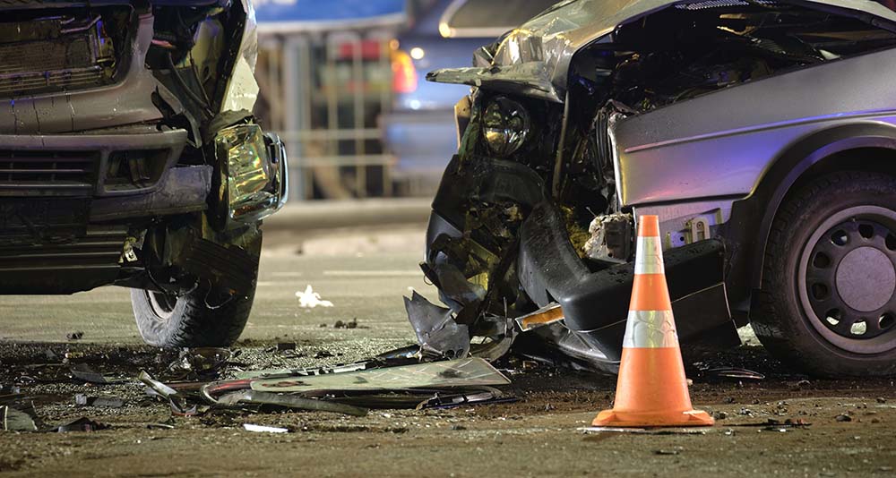 Two heavily damaged vehicles at night after crash