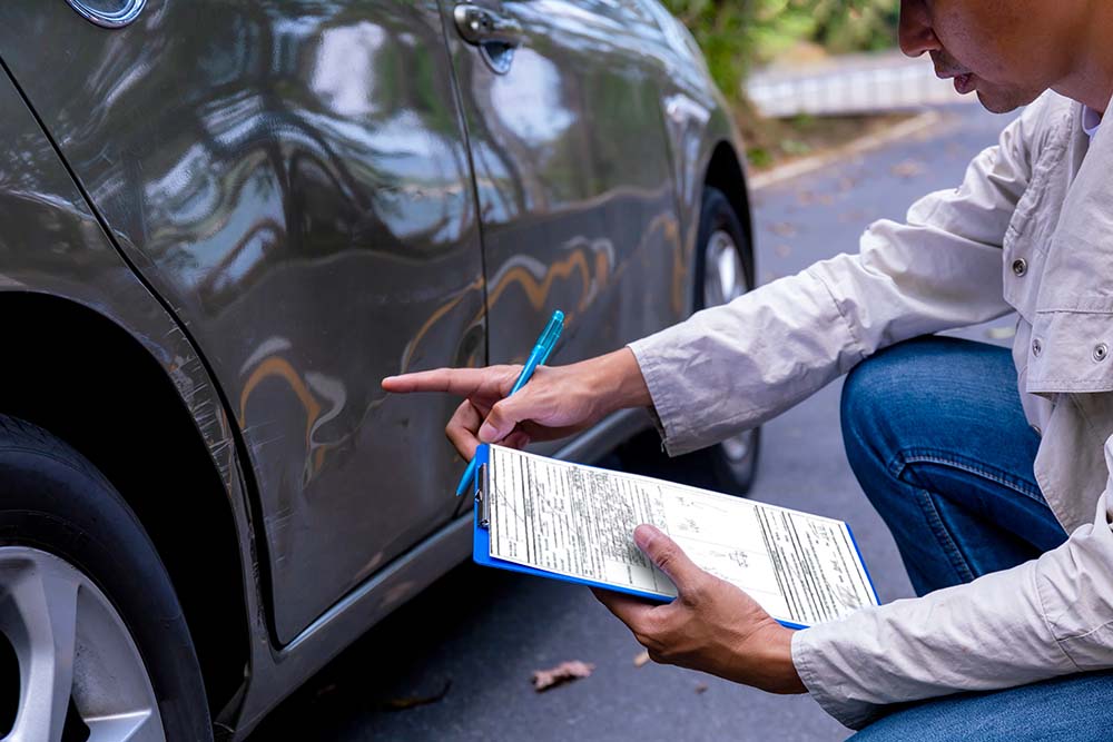 Close up of an insurance agent loss adjuster checking damage and writing accident report