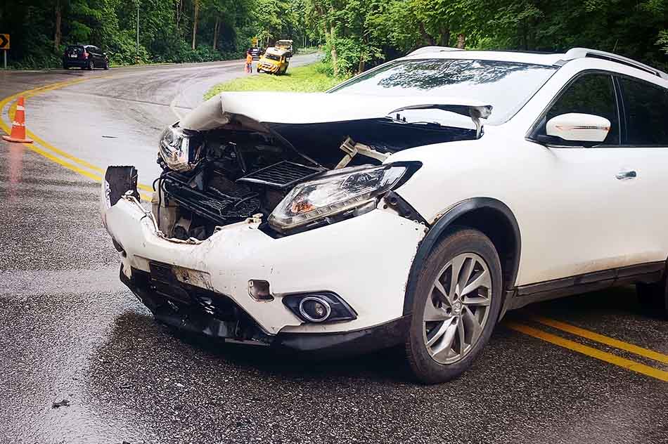 The smashed front end of a white car after an accident