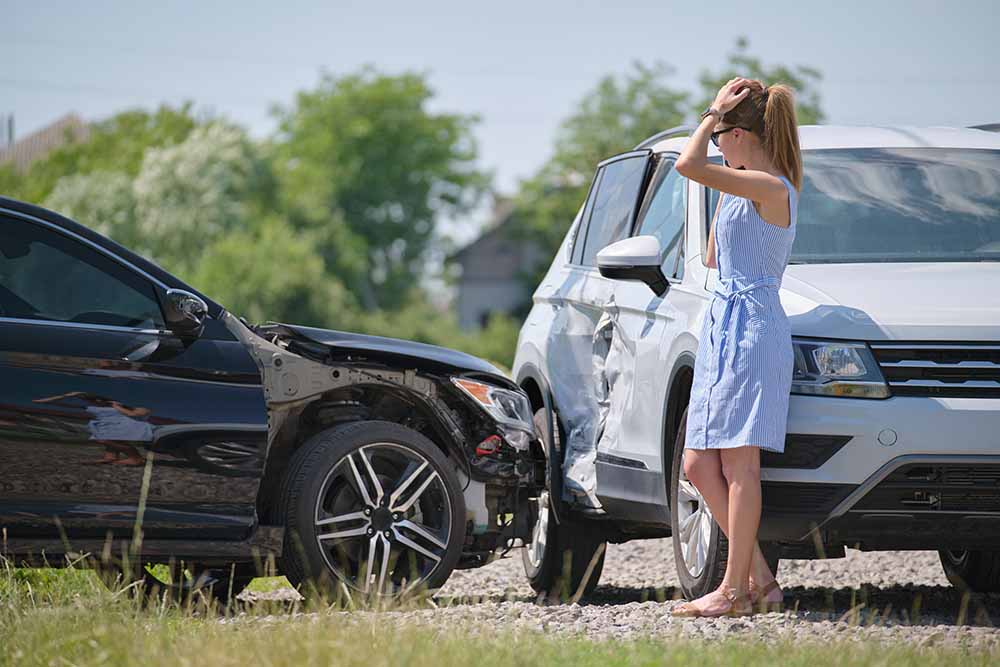 A woman standing in front of an accident holding her head